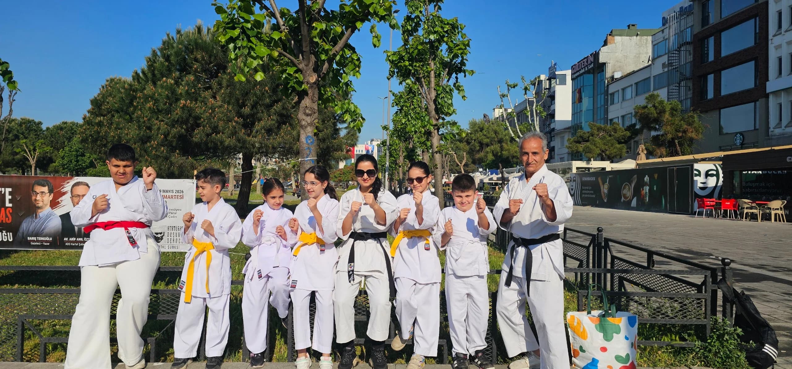 Kartal Karate Academy students in white karate gi with yellow, orange and black belts standing in fighting stance outdoors in Kartal, Istanbul