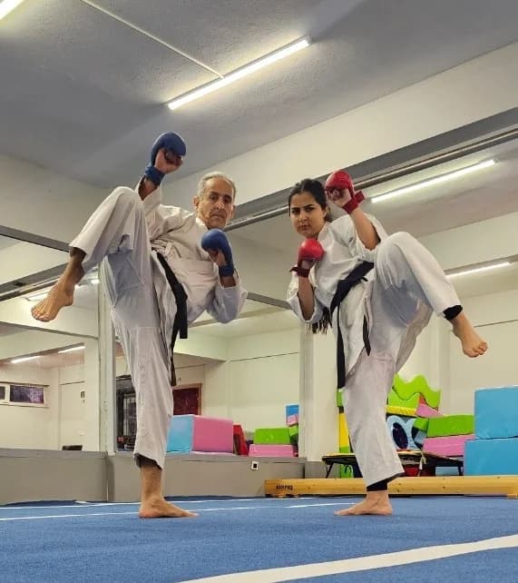 Sensei Behzad and Sensei Homa Yaghoubian performing simultaneous high kicks with sparring mitts during karate training at Yakacik Sports Club, Kartal