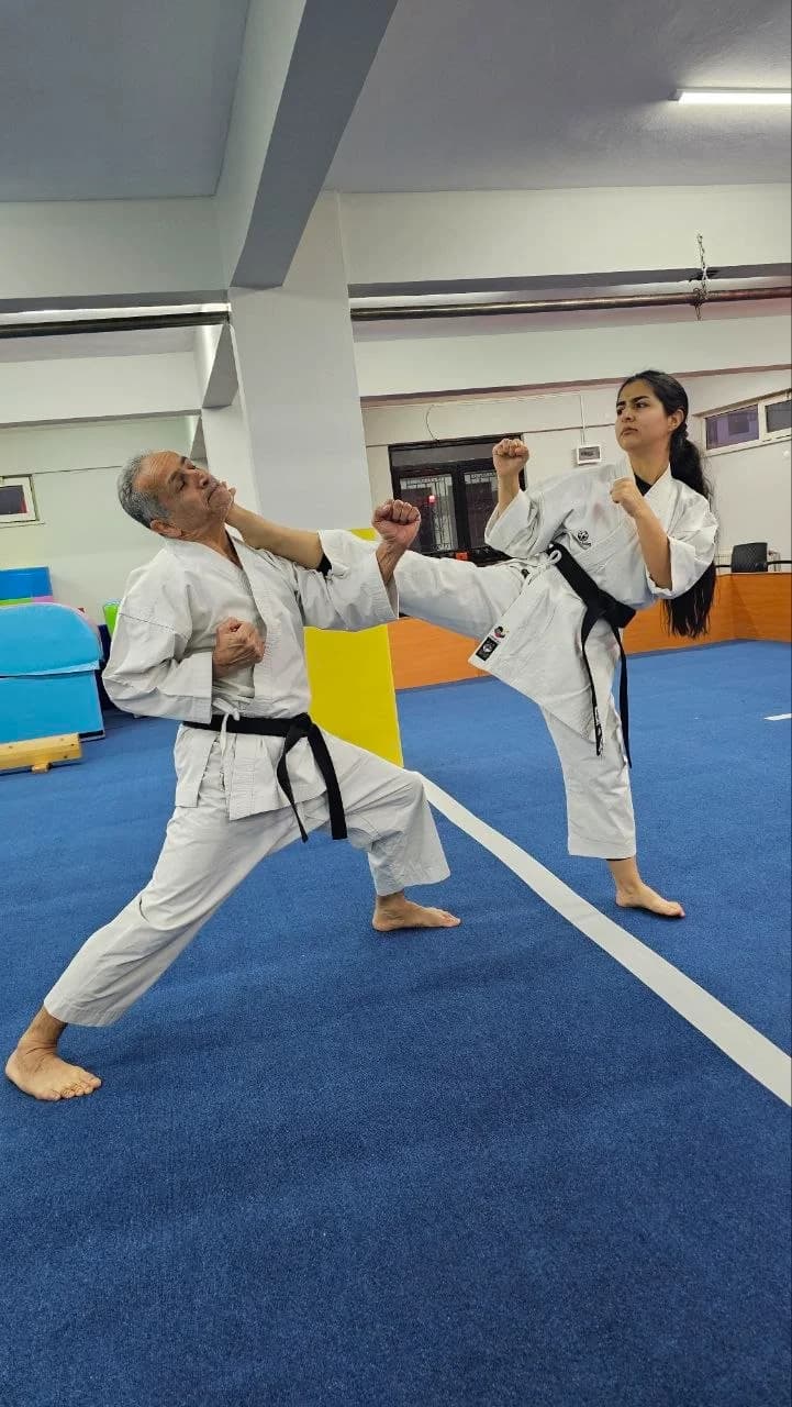 Black belt kumite training at Kartal Karate Academy, instructor and student practising kicking technique on the dojo mat